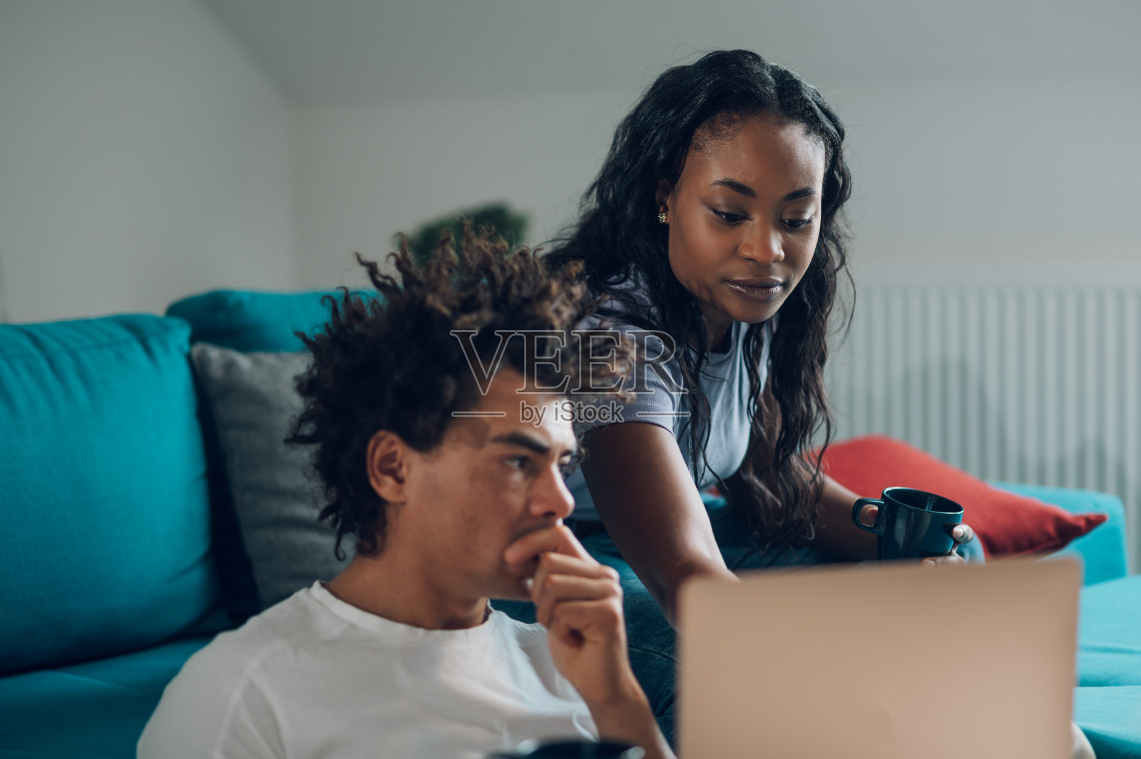 一对非洲裔美国夫妇在家里的沙发上放松着笔记本电脑和咖啡照片摄影图片