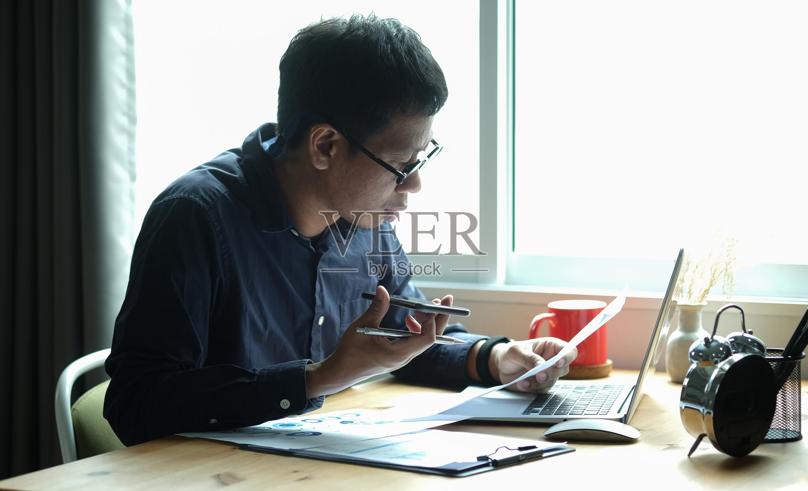 聪明的亚洲商人用手机和笔记本电脑工作。照片摄影图片