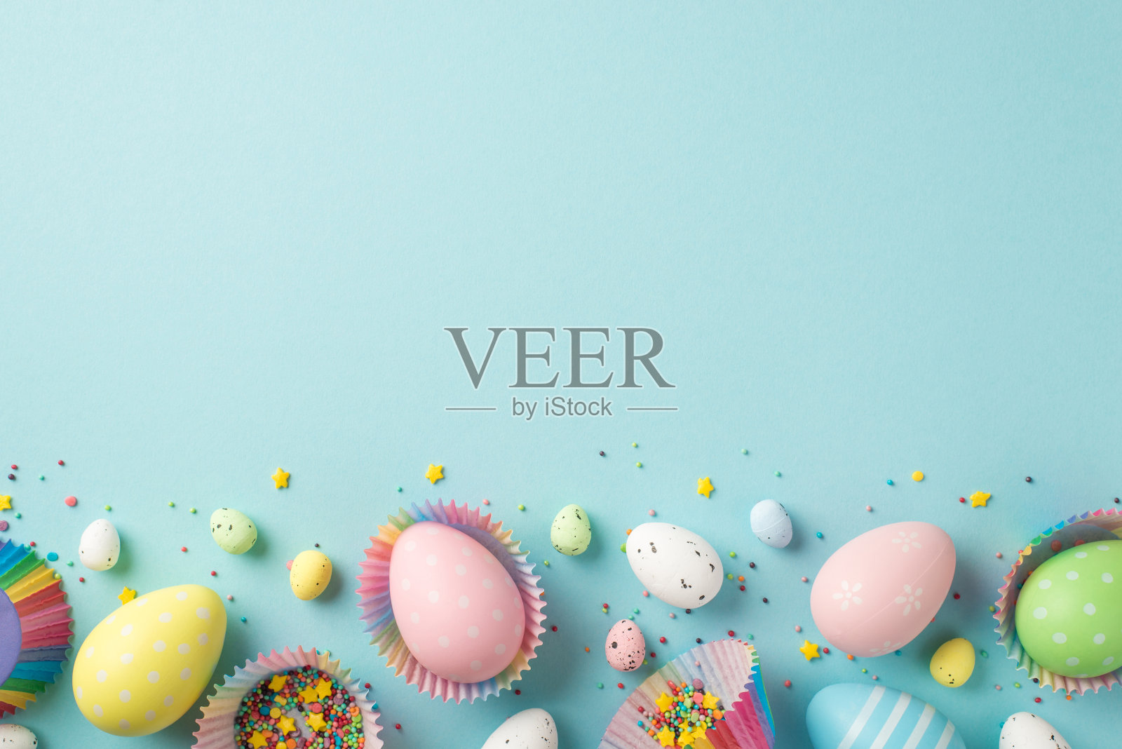 复活节装饰的俯视图照片在纸烘烤模具和糖果装饰在孤立的粉彩蓝色背景与copyspace照片摄影图片