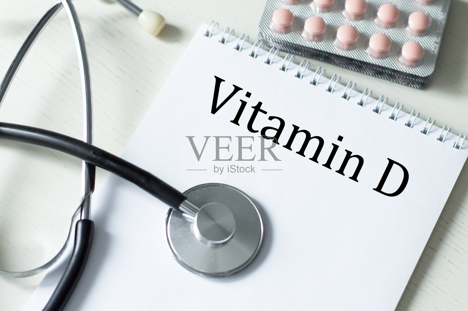 维生素d放在桌上听诊器旁边的笔记本和药片上照片摄影图片