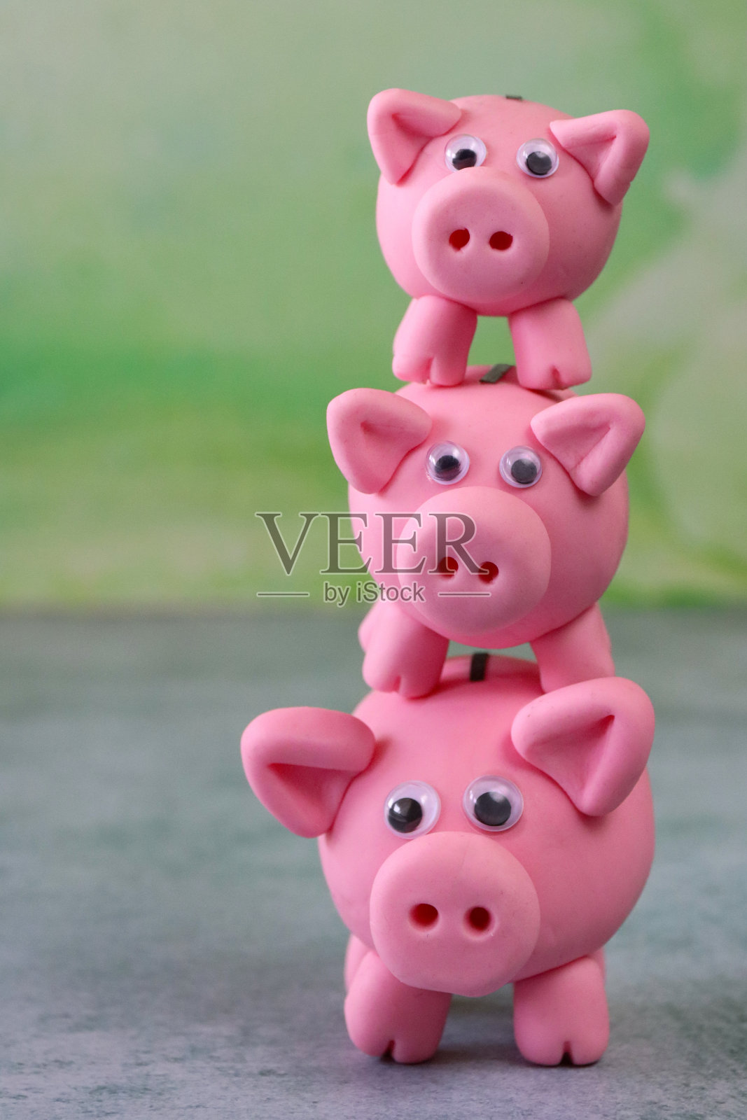 三个模型储蓄罐的堆叠图像，重点前景，斑纹绿色背景，家庭理财和储蓄概念照片摄影图片