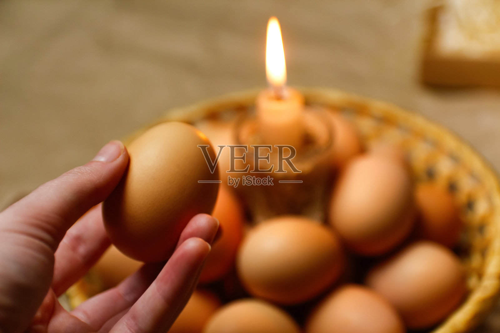 手拿着鸡蛋。蜡烛光。乡村背景。复活节的鸡蛋,Pysankas。收集鸡蛋的背景。为假期做准备。牛皮纸。传统。正统的照片摄影图片