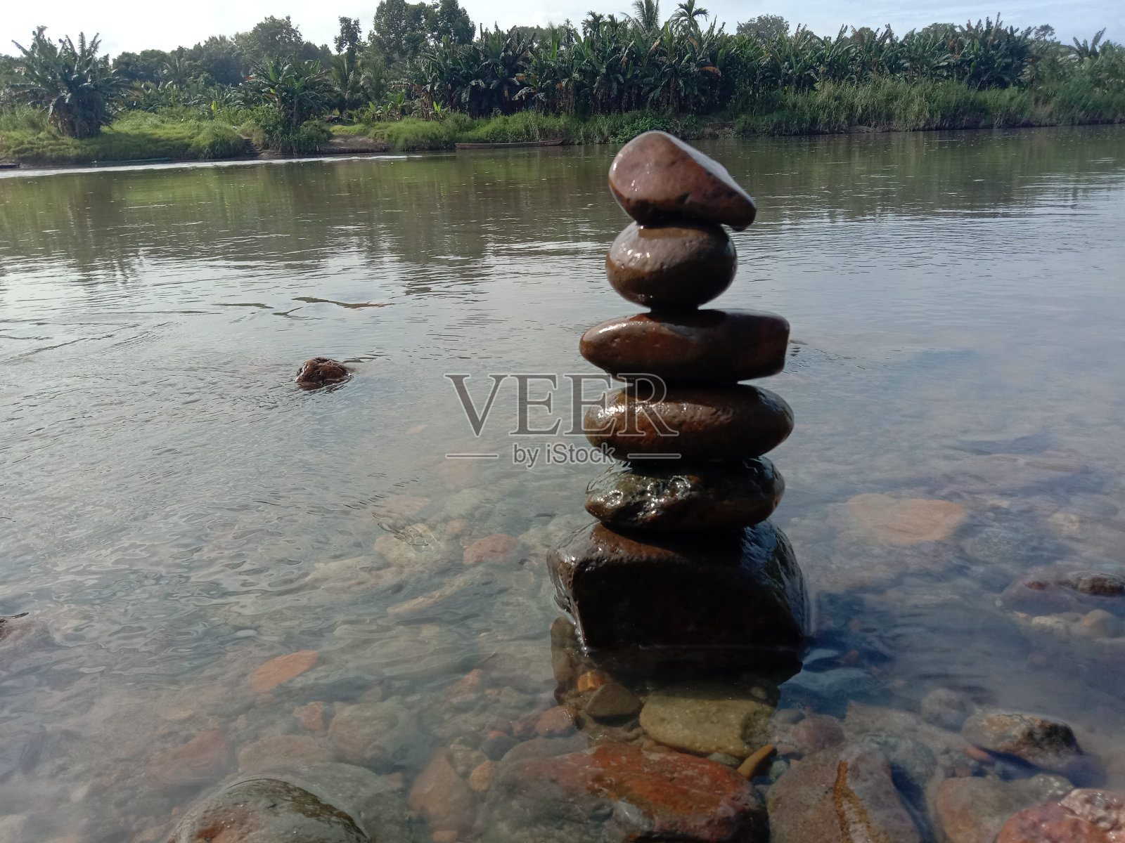 岩石在河边保持平衡。与自己和平相处。照片摄影图片