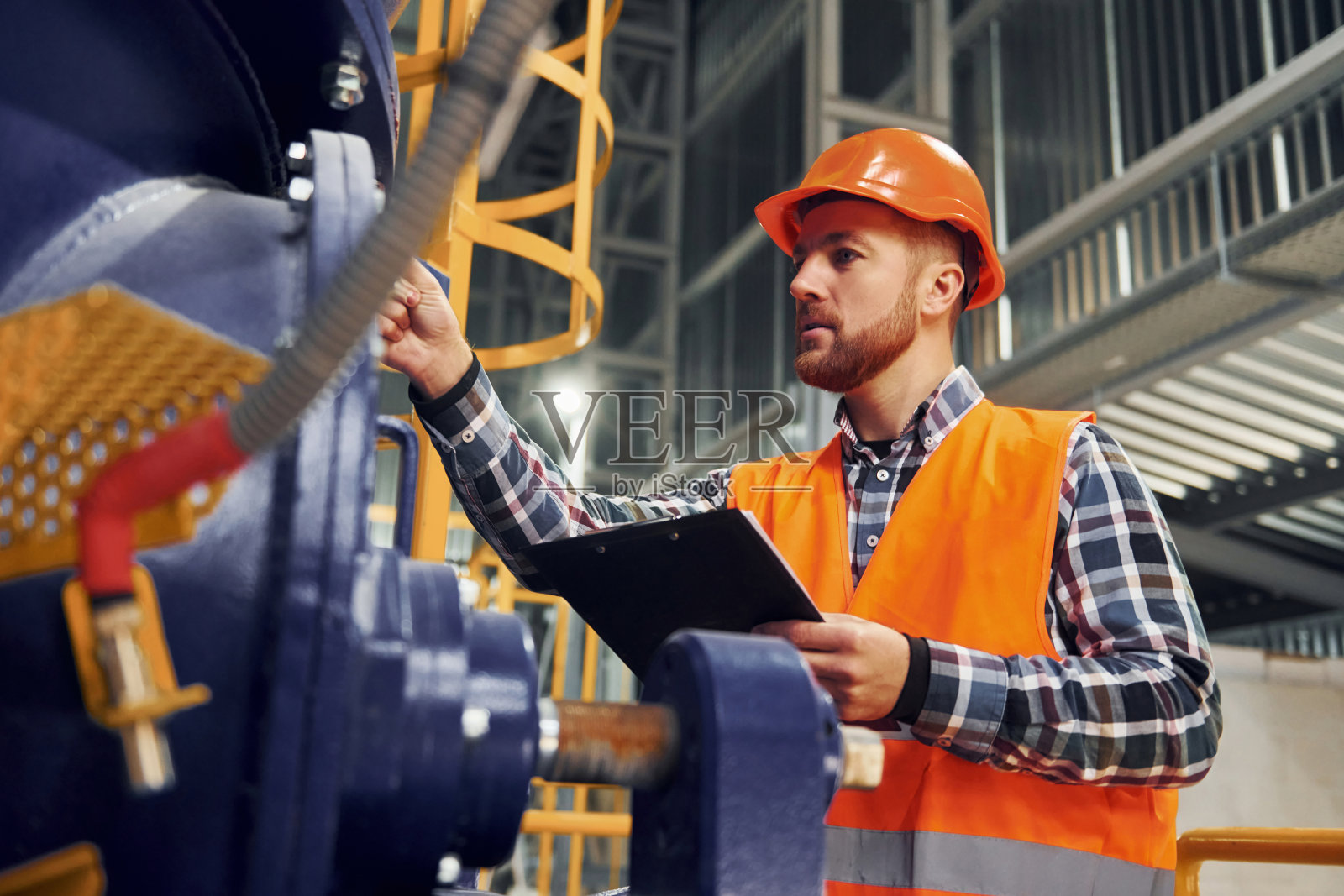 用记事本。穿制服的建筑工人在工厂里照片摄影图片