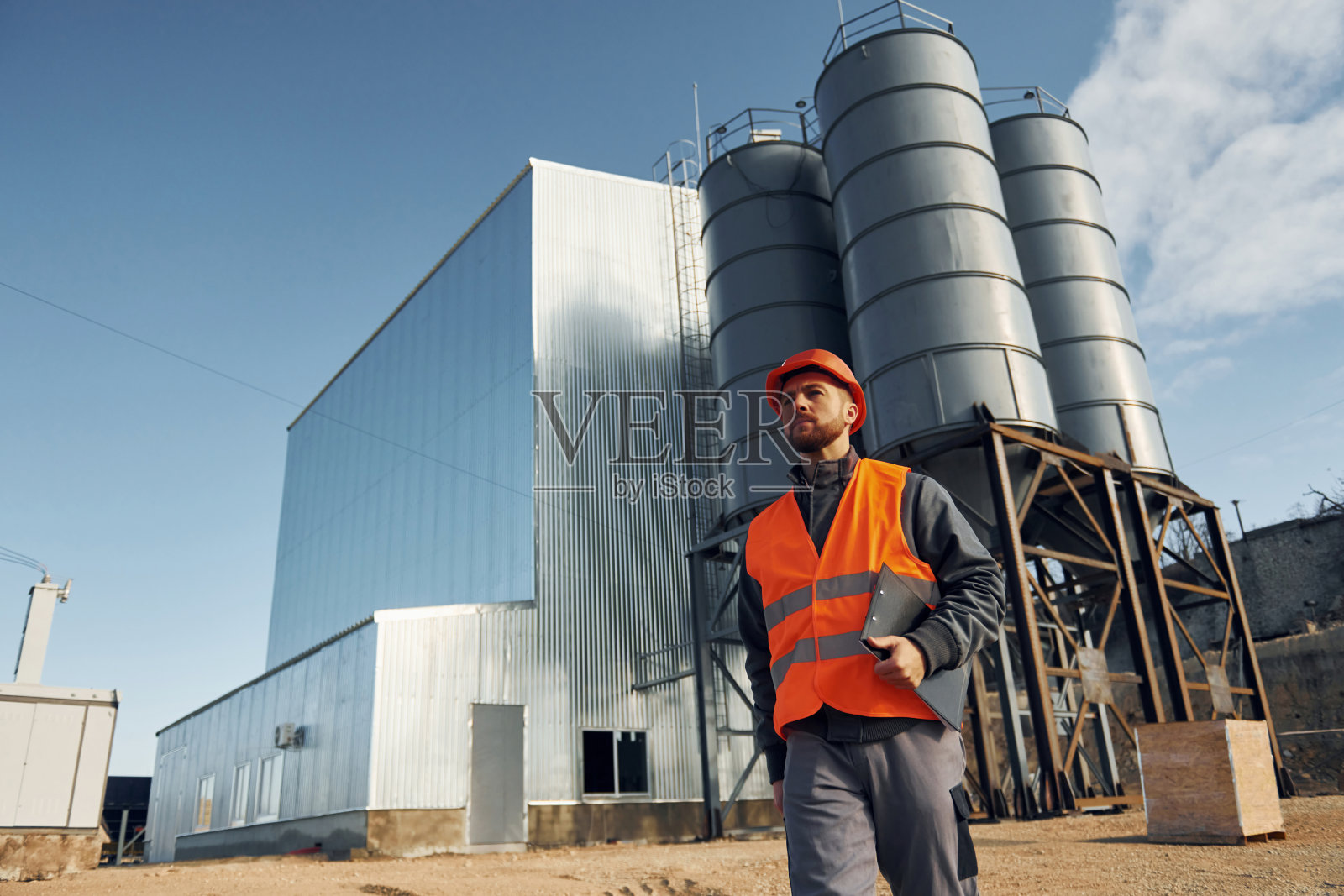 建筑外观。穿制服的建筑工人在工厂附近的户外活动照片摄影图片
