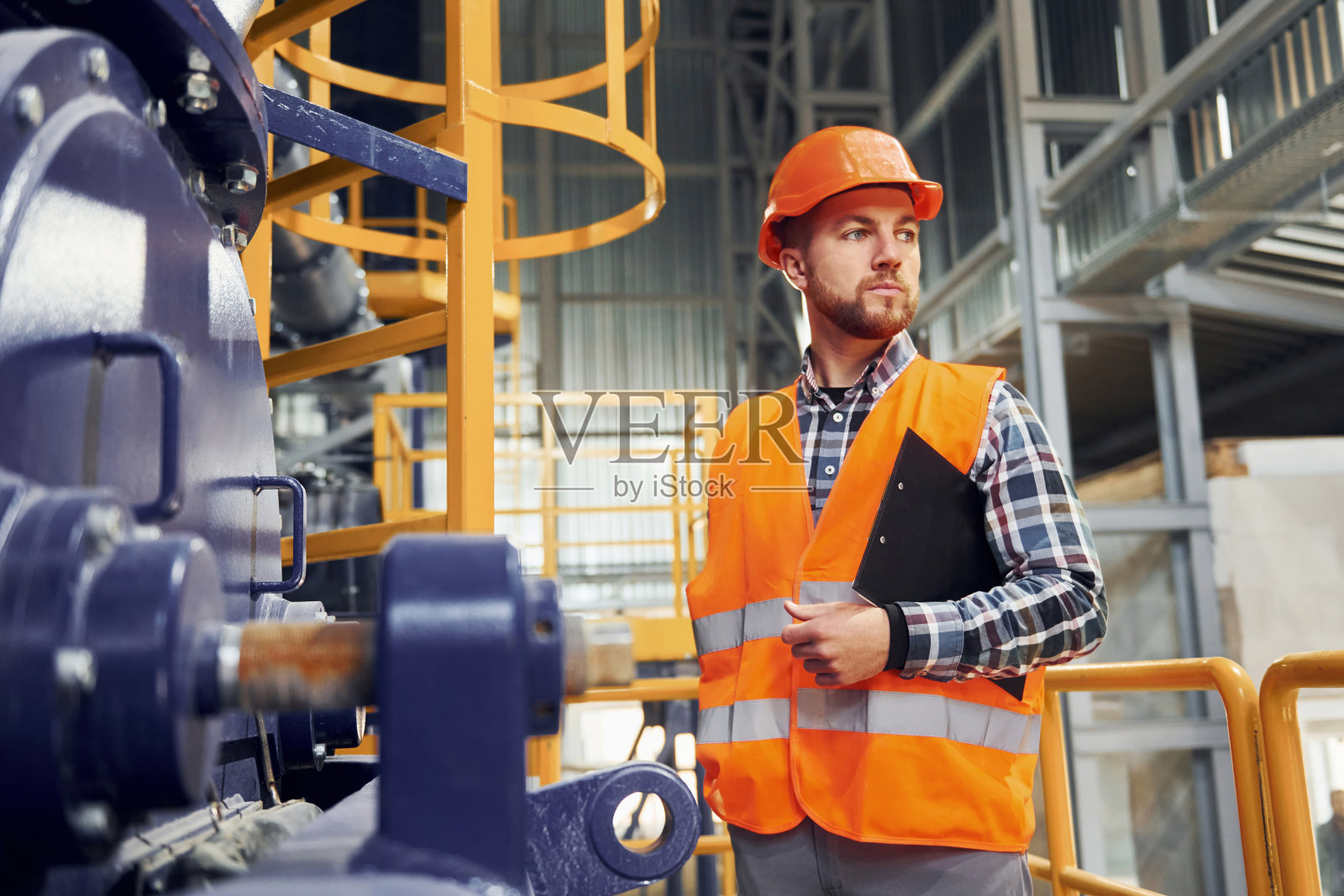 用记事本。穿制服的建筑工人在工厂里照片摄影图片