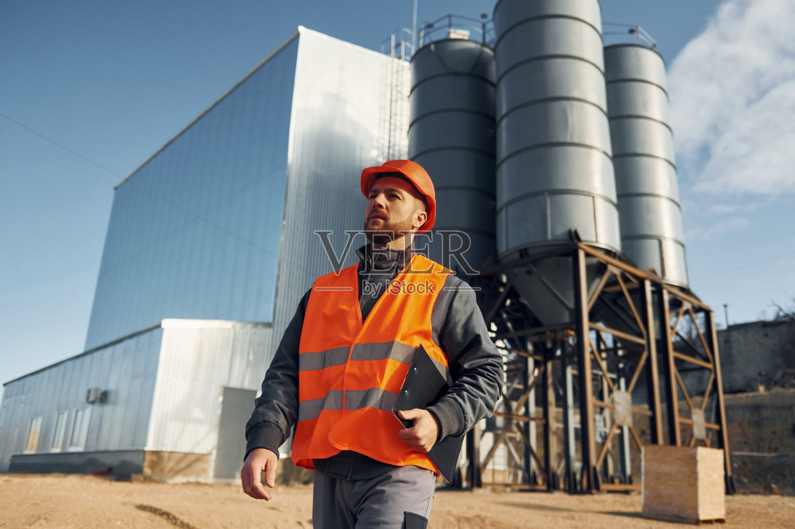 建筑外观。穿制服的建筑工人在工厂附近的户外活动照片摄影图片