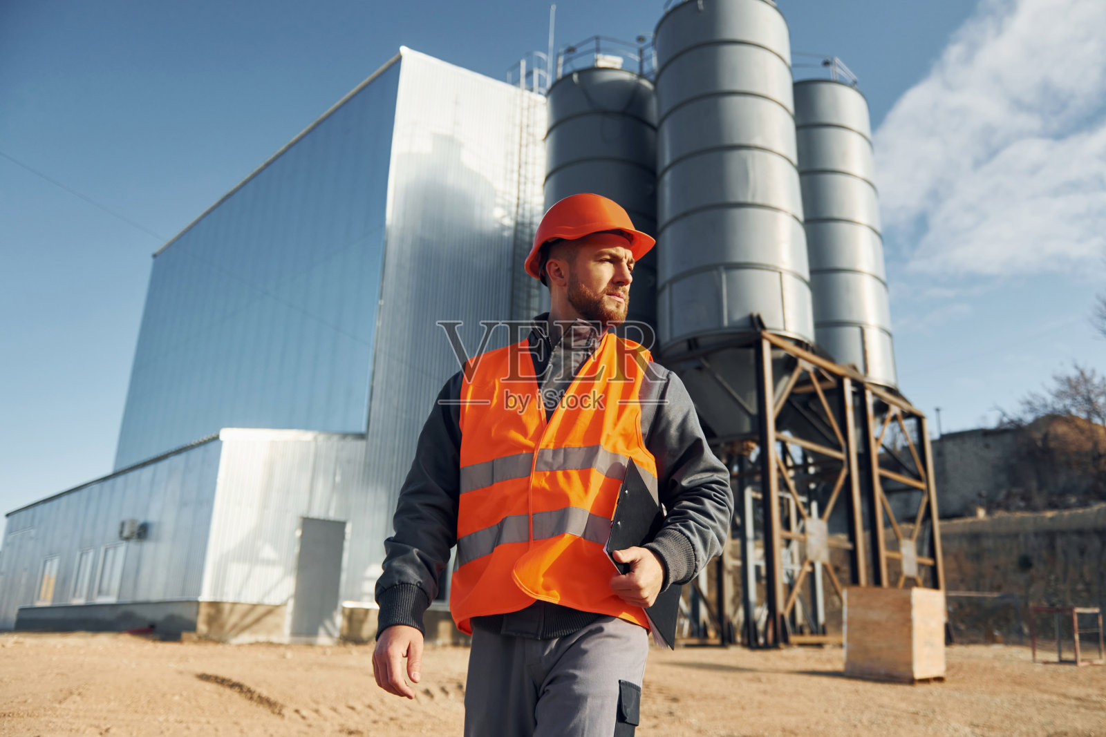 建筑外观。穿制服的建筑工人在工厂附近的户外活动照片摄影图片