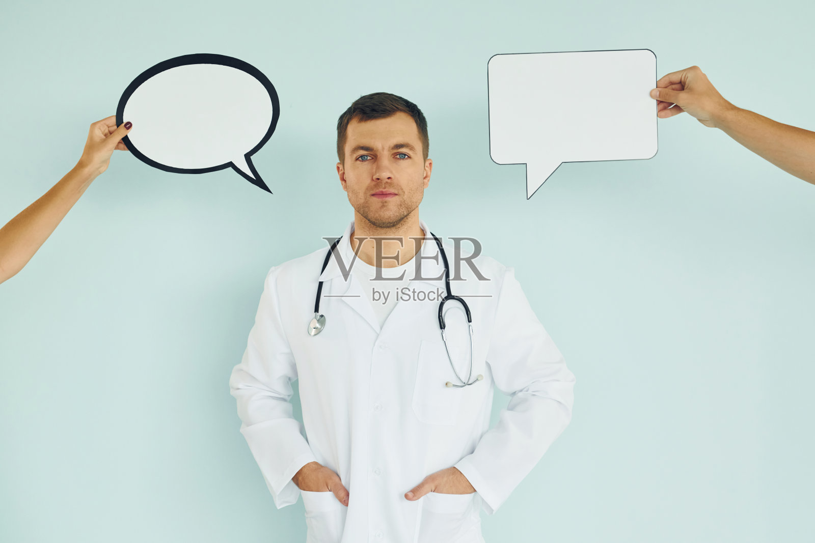 在医生的制服。一个男人站在画室里，手里拿着空白的牌子照片摄影图片