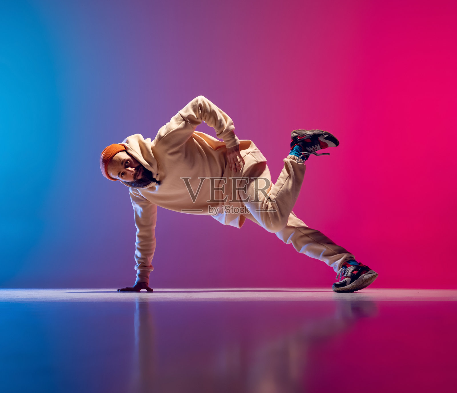 工作室拍摄的年轻灵活的运动男子舞蹈霹雳舞在白色的服装梯度粉蓝色的背景。行动、艺术、美、运动、青春的概念照片摄影图片