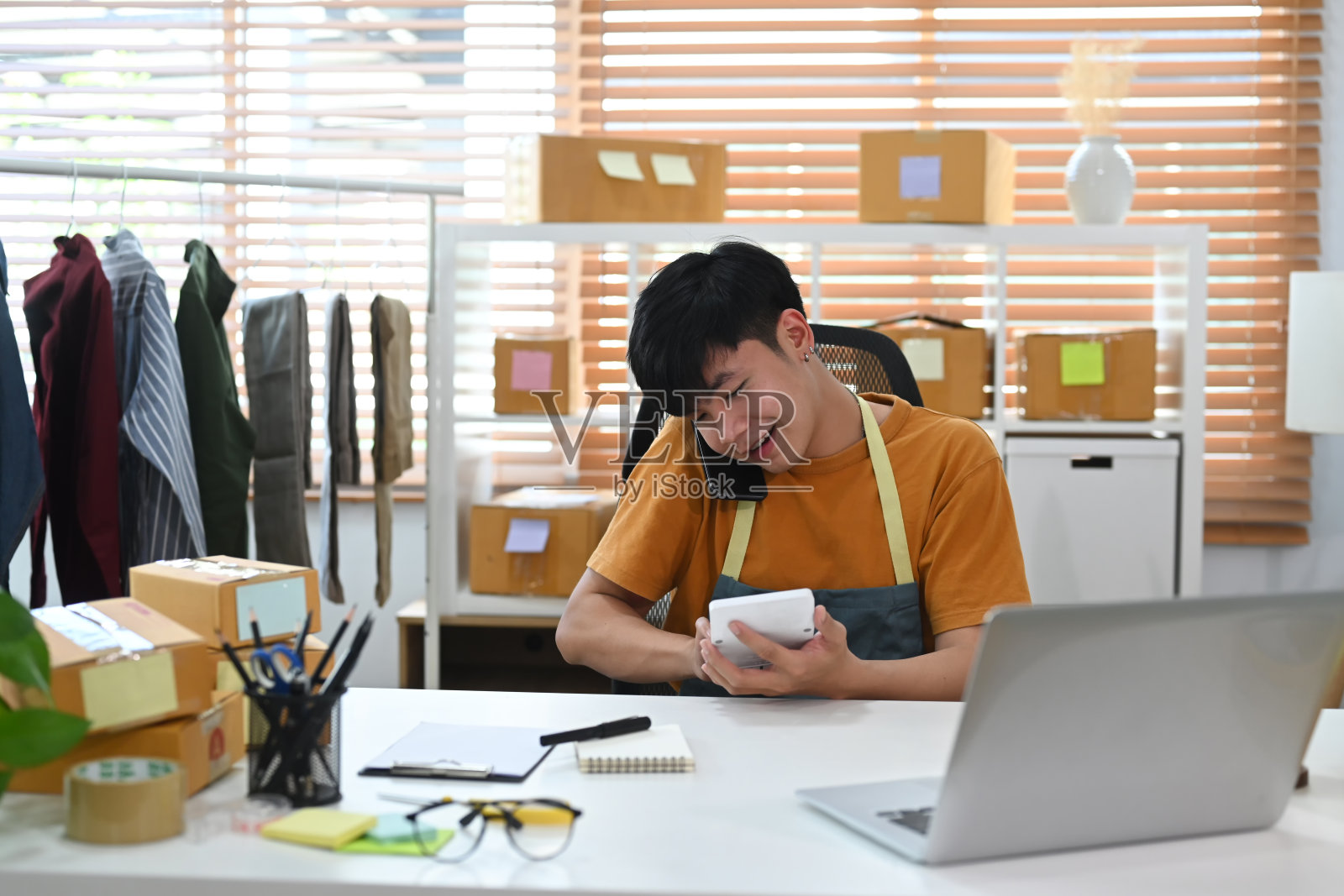 穿着围裙的小企业主用手机接顾客的订单。照片摄影图片