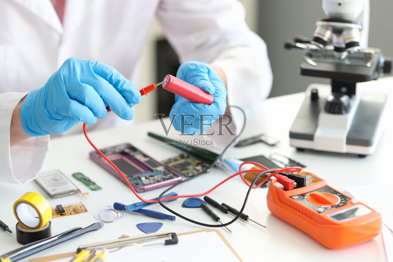 一个穿着制服的人手里拿着电压表和红色电池照片摄影图片