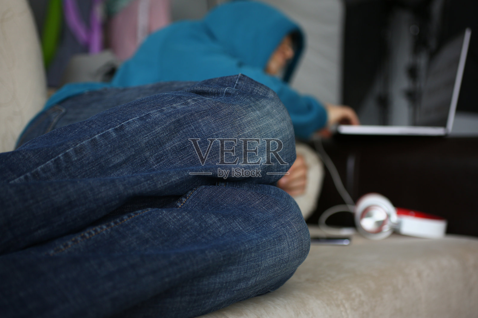 人们跪在沙发上，男人在家里拿着笔记本电脑和耳机照片摄影图片