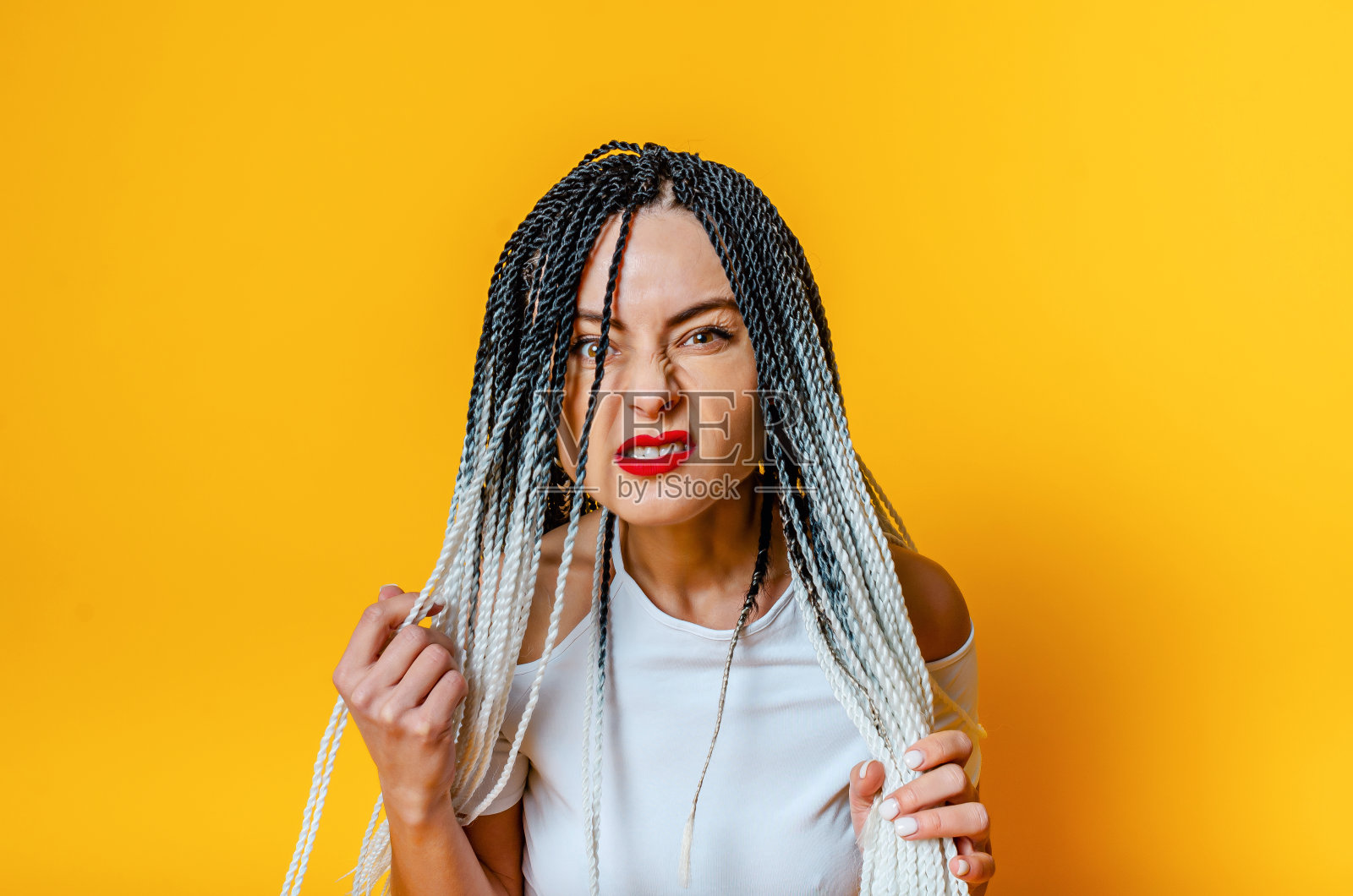 一个留着脏辫的愤怒女人的肖像。红色的口红。手中持有的小辫儿。照片摄影图片