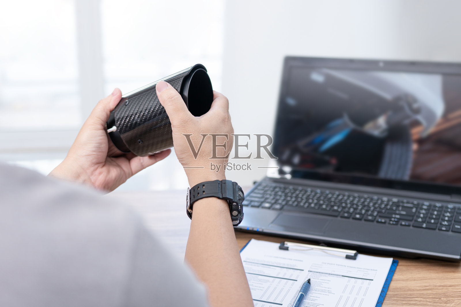 近手一名男子拿着汽车尾气和规格检查汽车配件美容和检查表笔记本电脑上，修改汽车概念照片摄影图片