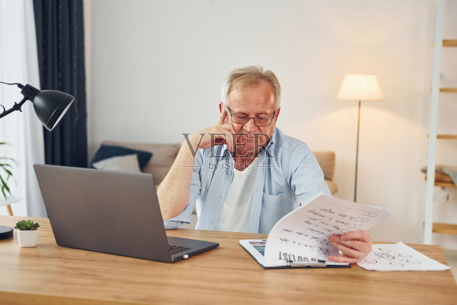 使用笔记本电脑工作。穿着漂亮衣服的老先生在家照片摄影图片