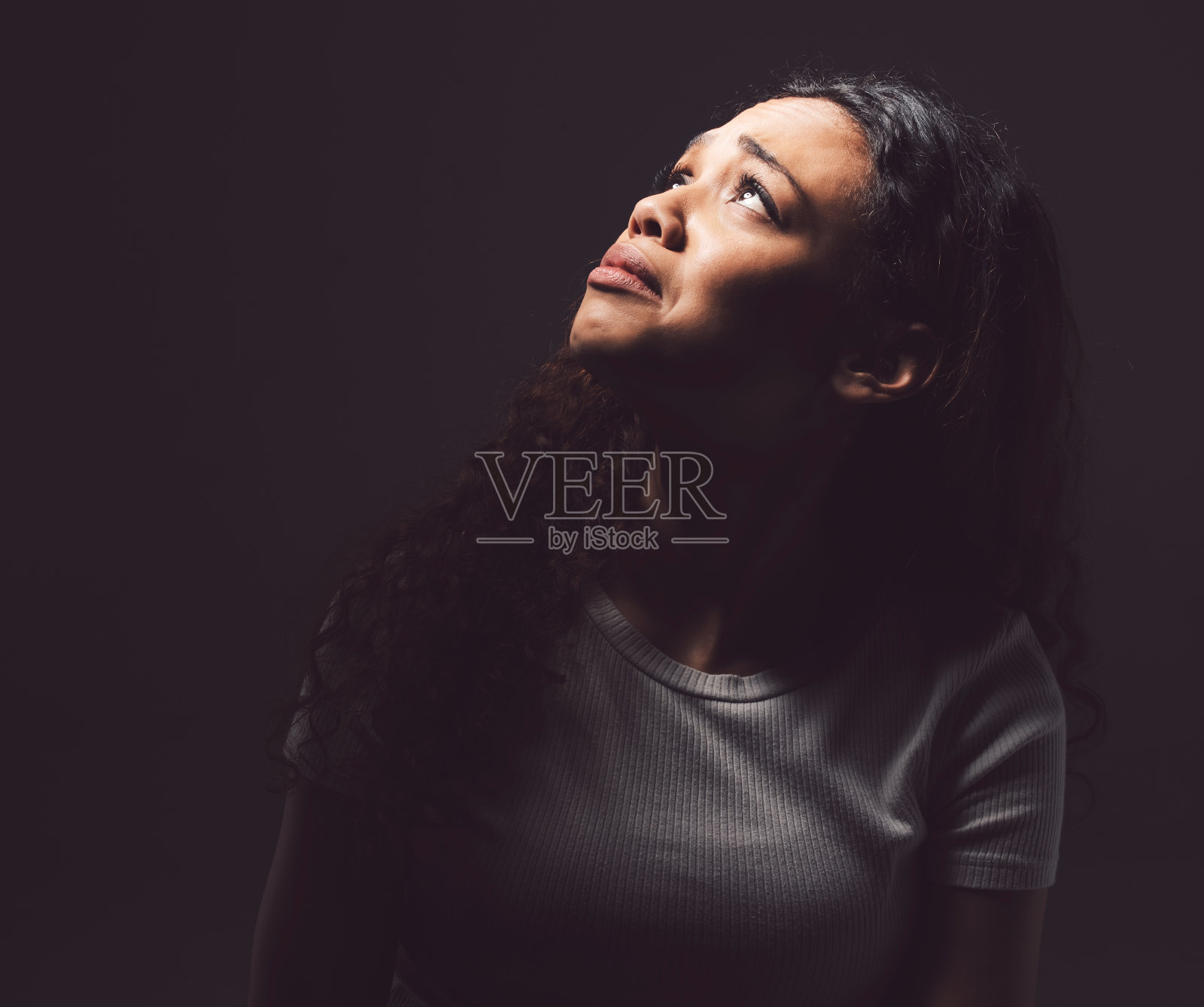 一名年轻女子在黑色背景下哭泣照片摄影图片