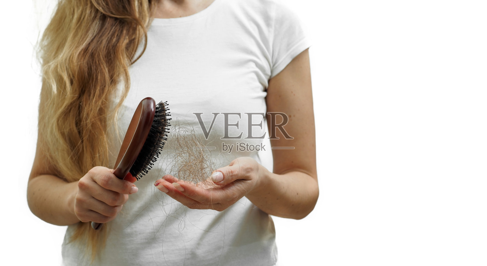 一个长着金色长发的女孩手里拿着一把梳子，头发正在脱落。脱发的问题照片摄影图片