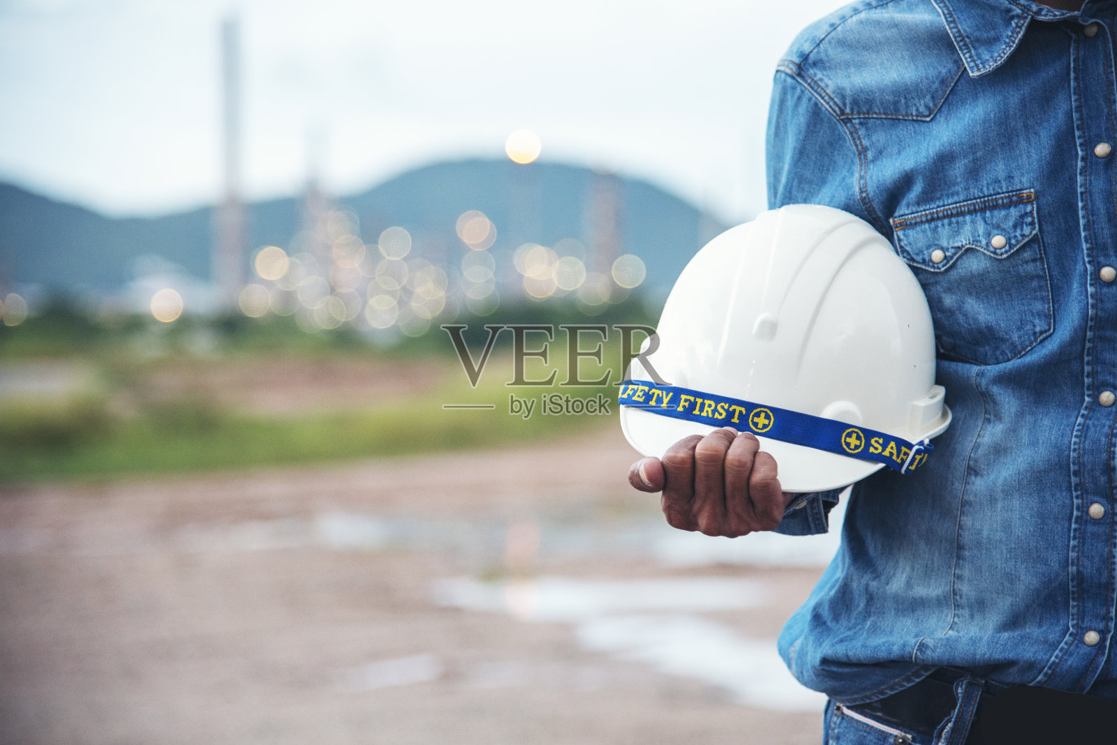 土木建筑工程工程师手持安全帽，白色安全帽。建筑工地的建筑工程师，身穿安全服，手持白色安全帽照片摄影图片