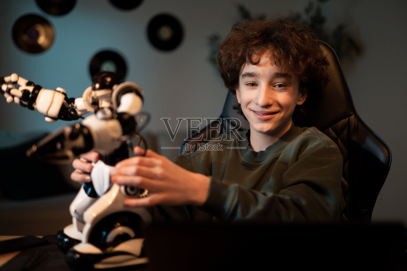 开朗、聪明的学生在课余时间坐在家里的书桌前构造机器人装置，孩子微笑着培养爱好照片摄影图片