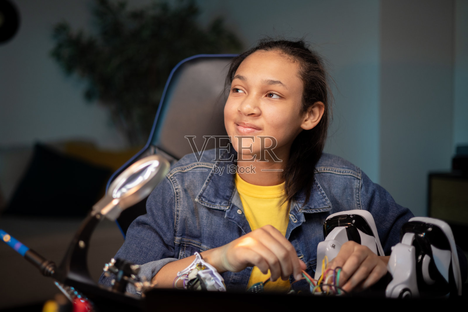 一个痴情的女孩看着旁边，想象着一个遥控机器人的原型，一个对机器人、电子产品感兴趣的青少年，制作玩具组件，连接电缆照片摄影图片