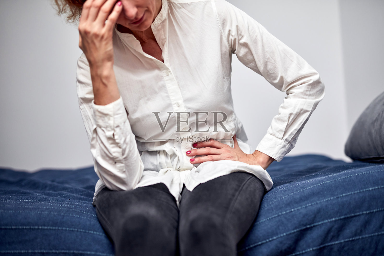 有强烈胃痛的女人在家。照片摄影图片