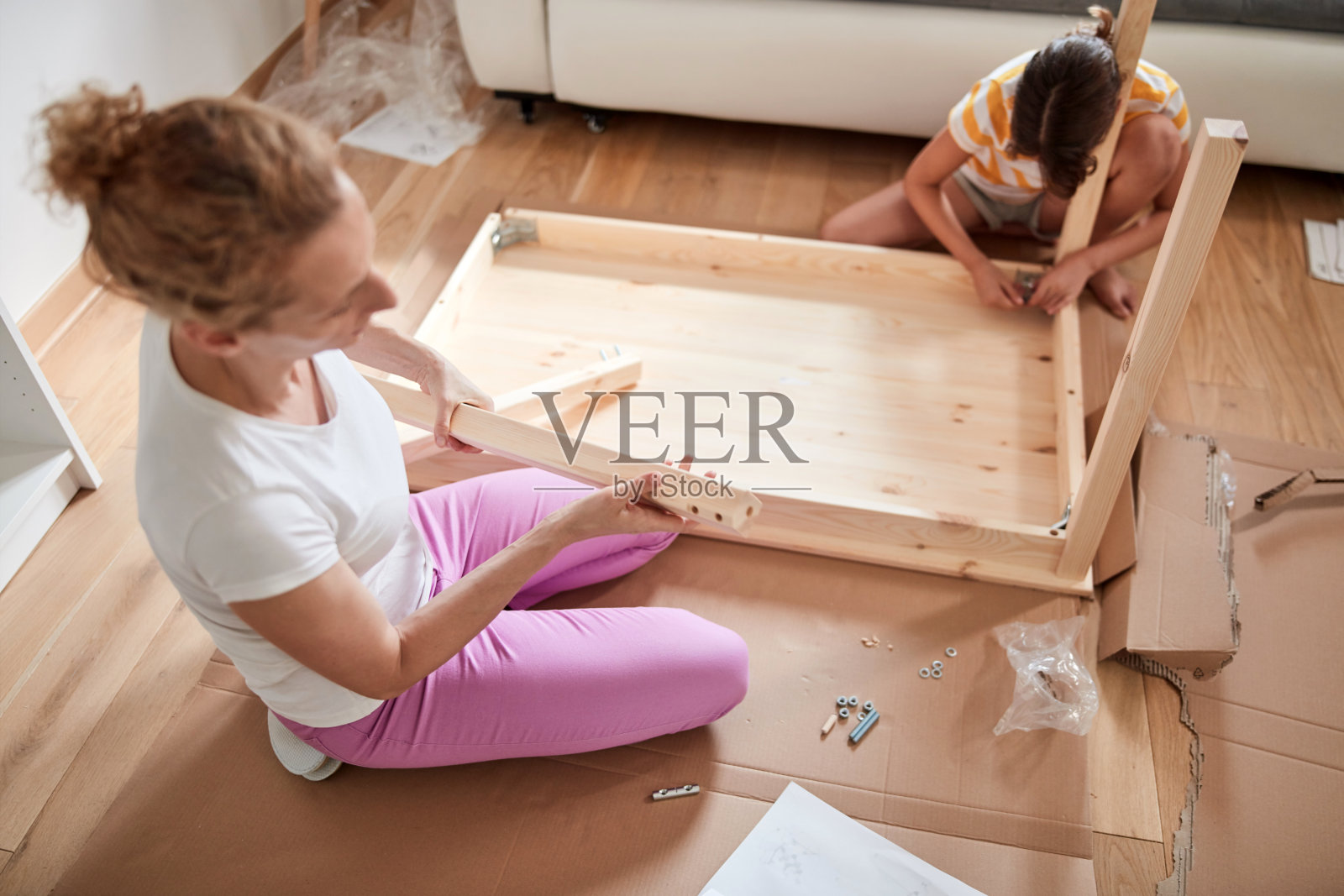 母女俩正在组装新家具——搬进新家。照片摄影图片