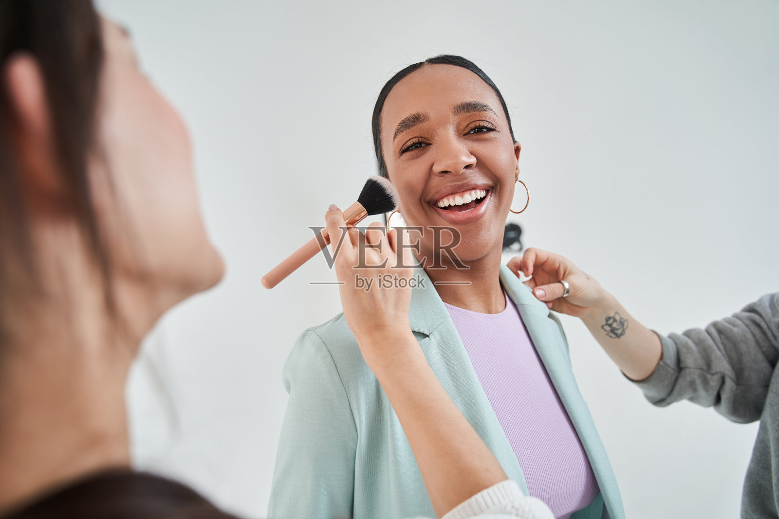 活泼的多种族女孩笑出声来，而团队的化妆师和造型师准备她的外观照片摄影图片