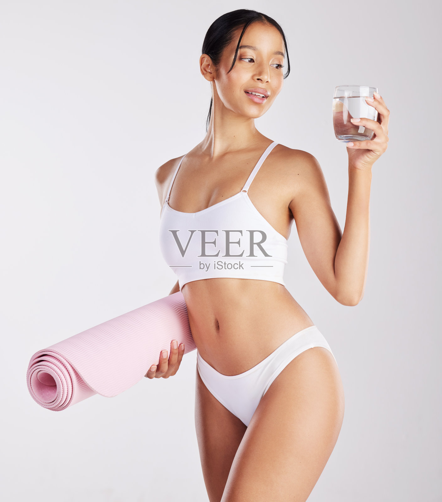 一个健康的年轻女人拿着一杯水和一个瑜伽垫的照片照片摄影图片