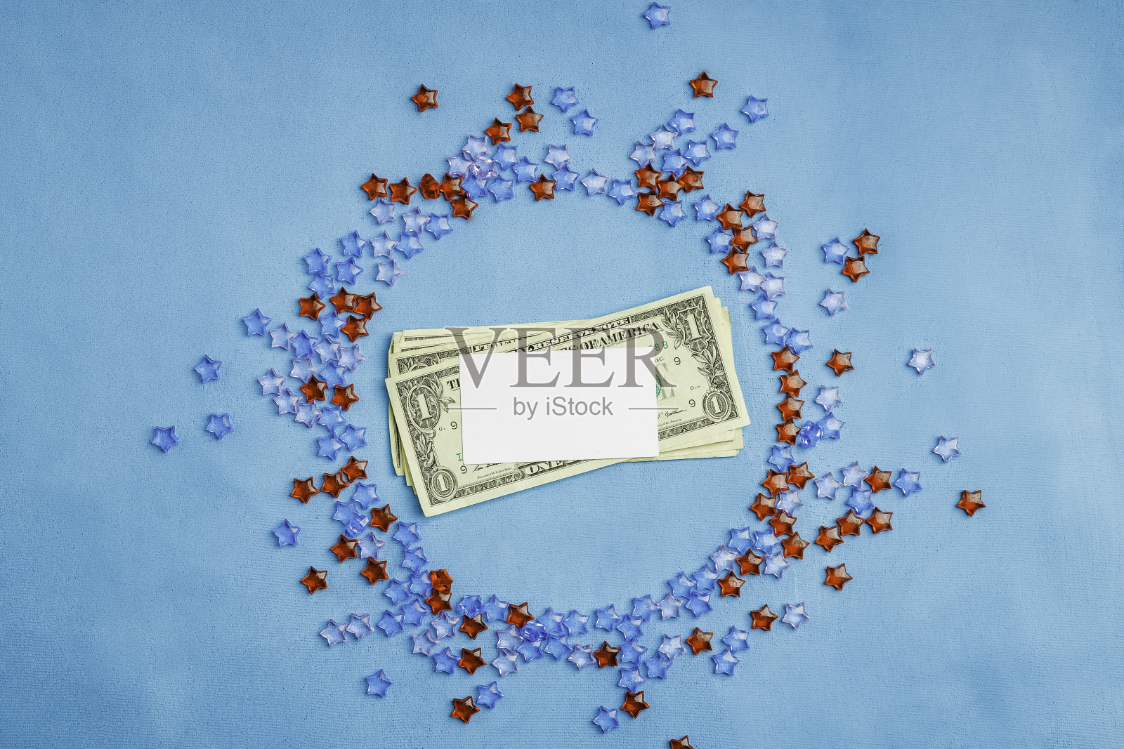 白色的名片上印着钱，周围是红色和蓝色的塑料星星照片摄影图片
