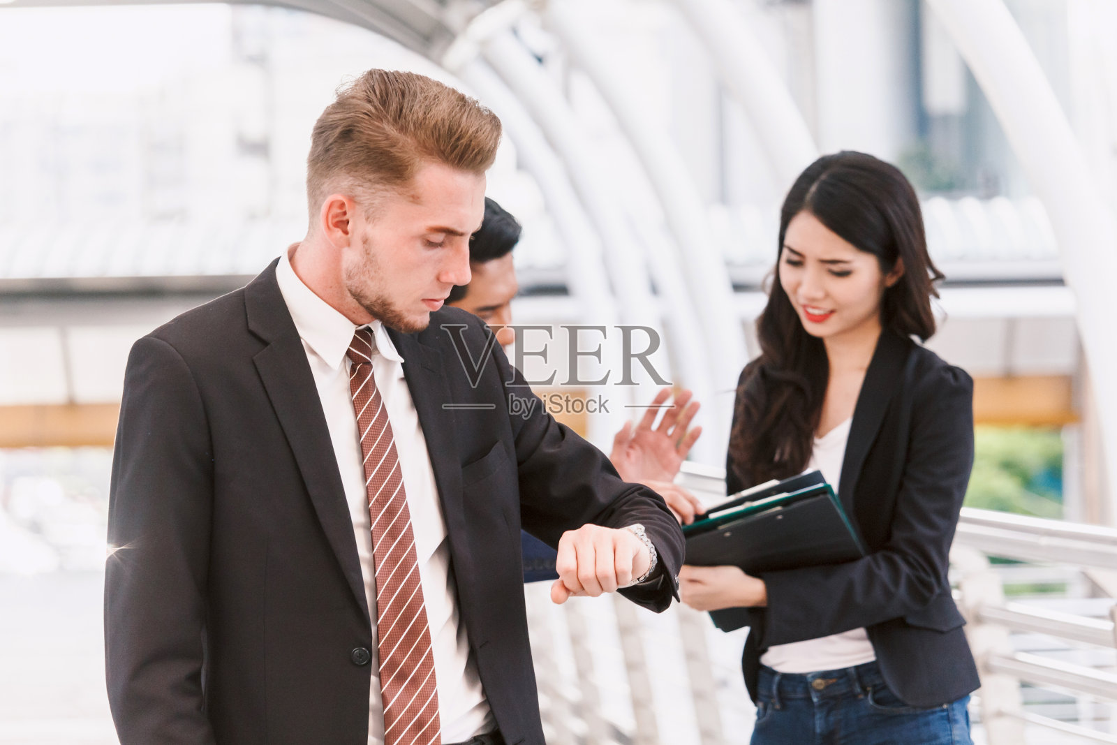 商人看着手表看着办公楼照片摄影图片