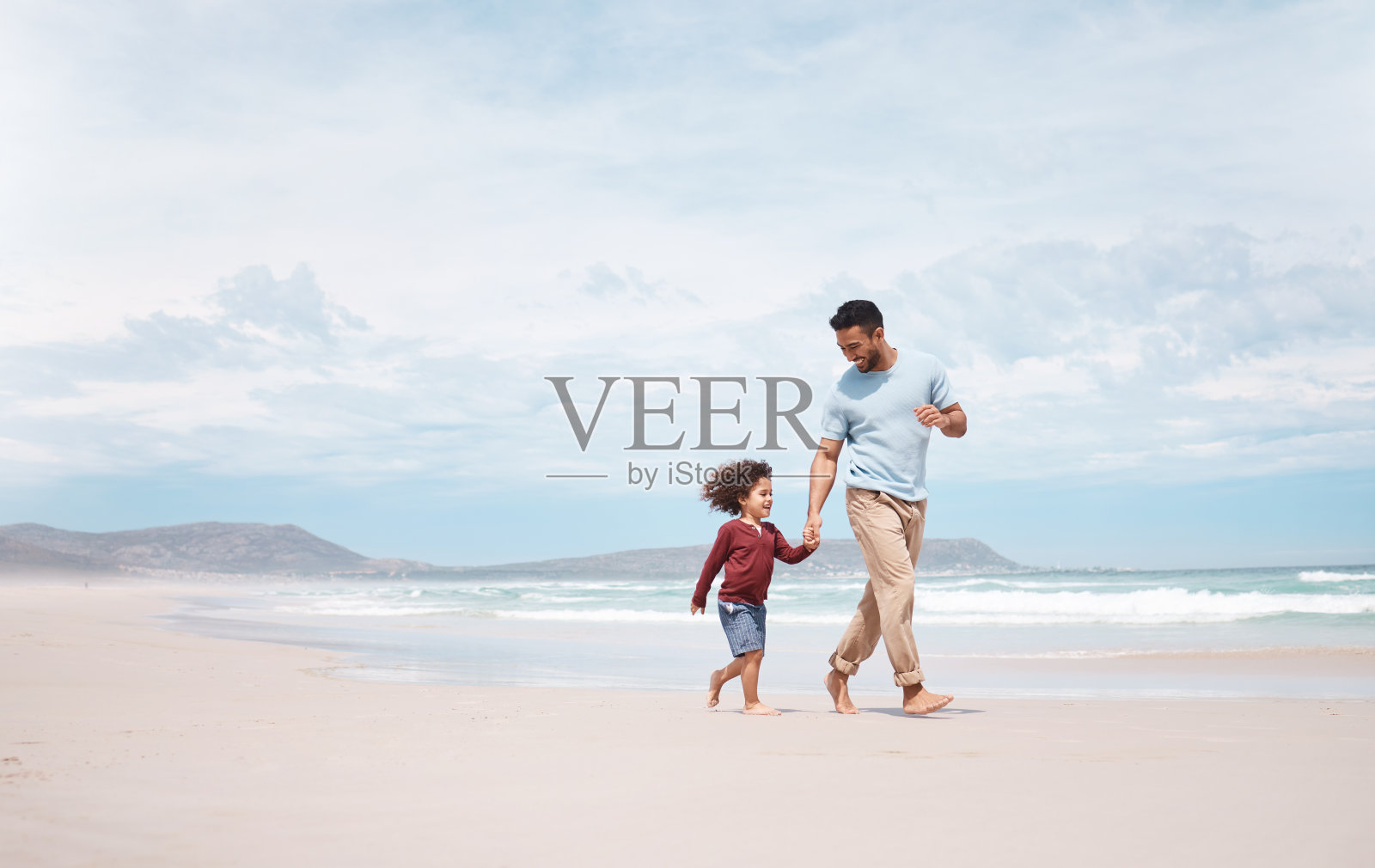 拍摄的是一个男人和他儿子在沙滩上玩耍照片摄影图片