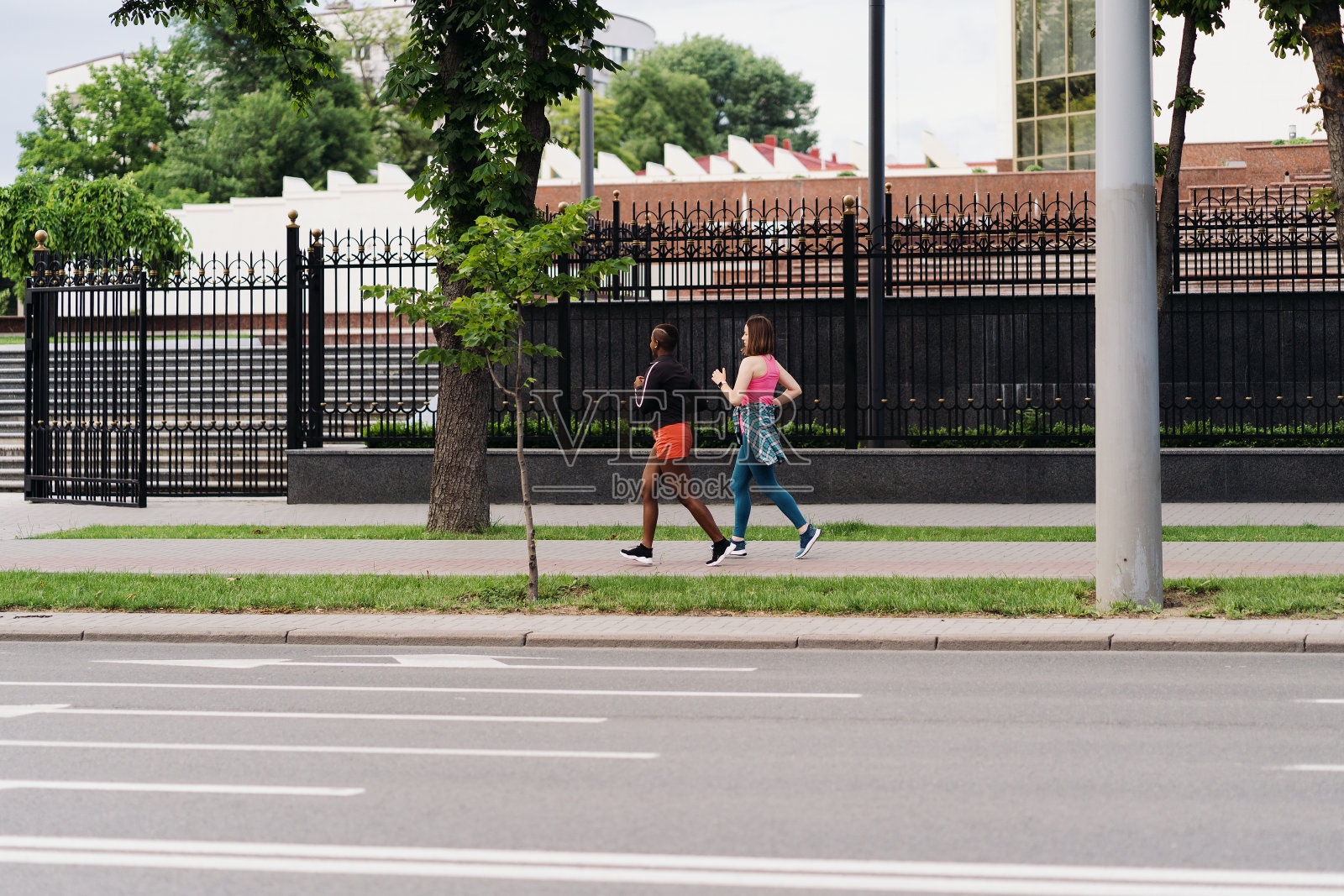 两个多民族女孩跑过城市的街道，在户外交流。照片摄影图片