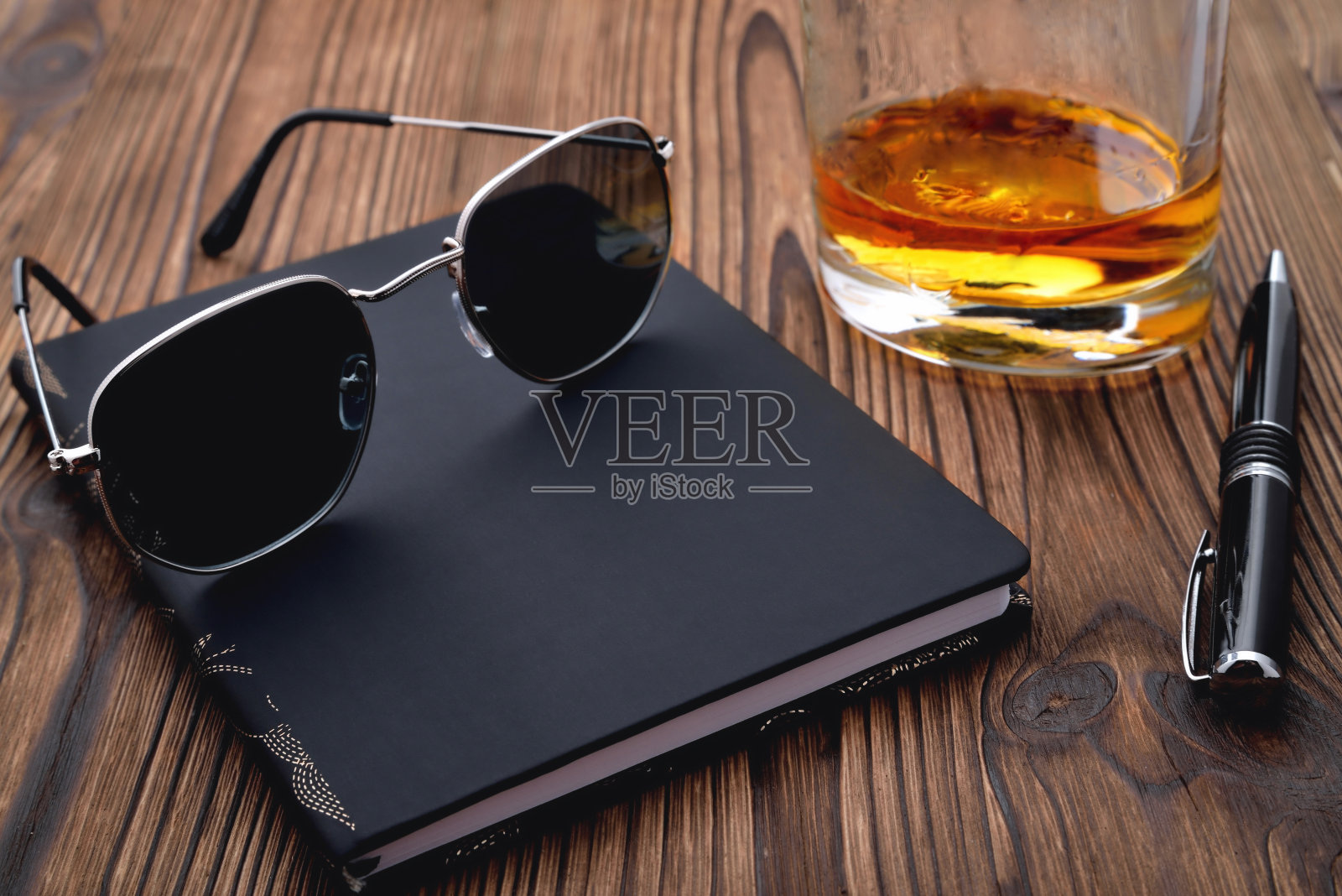 太阳眼镜黑色笔记本威士忌玻璃钢笔自然木制背景照片摄影图片