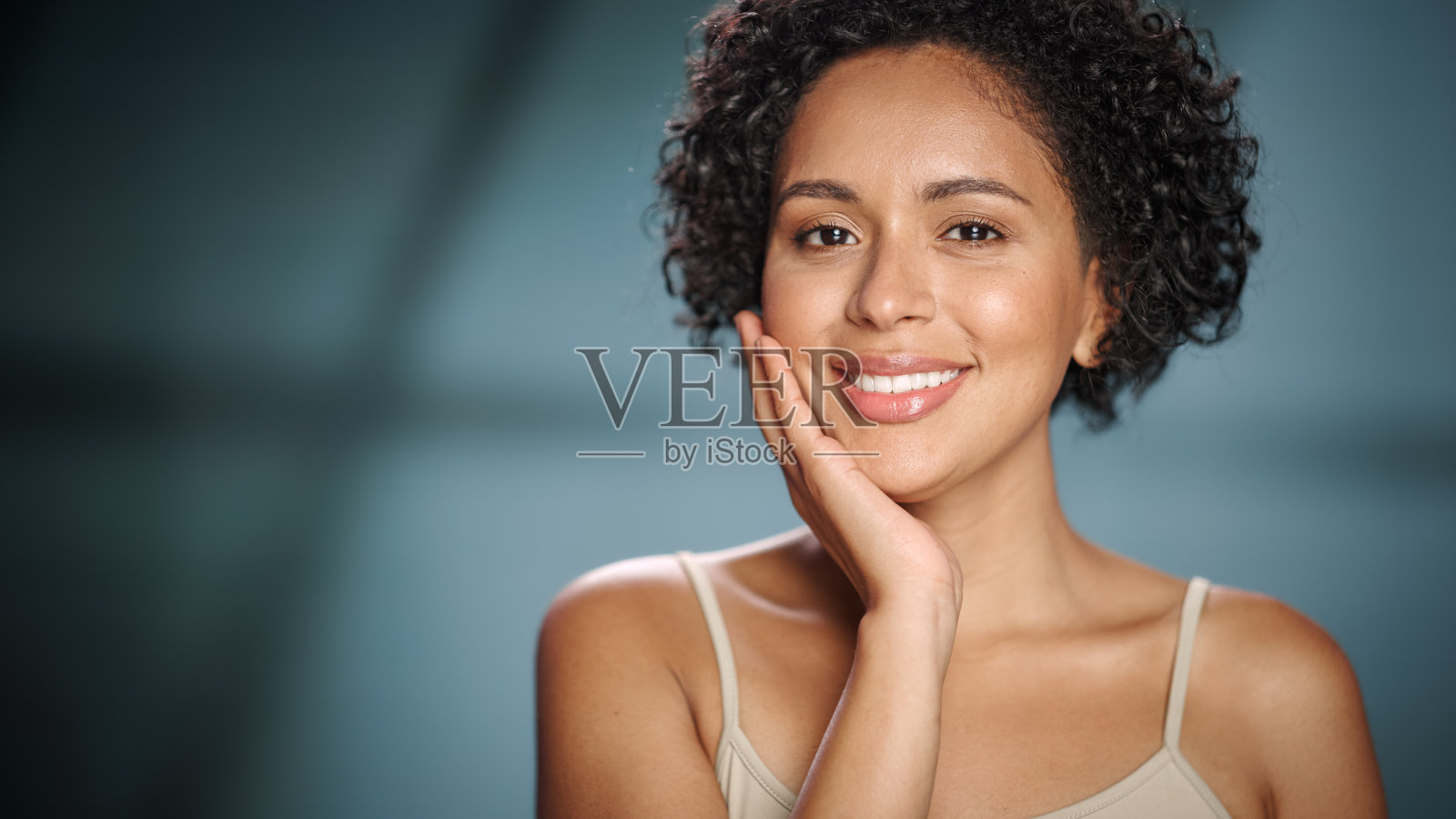 女性美丽的肖像。美丽的黑人多种族拉丁妇女与非洲发型摆姿势，触摸她的自然，健康的皮肤。柔软孤立背景下的健康护肤理念。关闭了。照片摄影图片