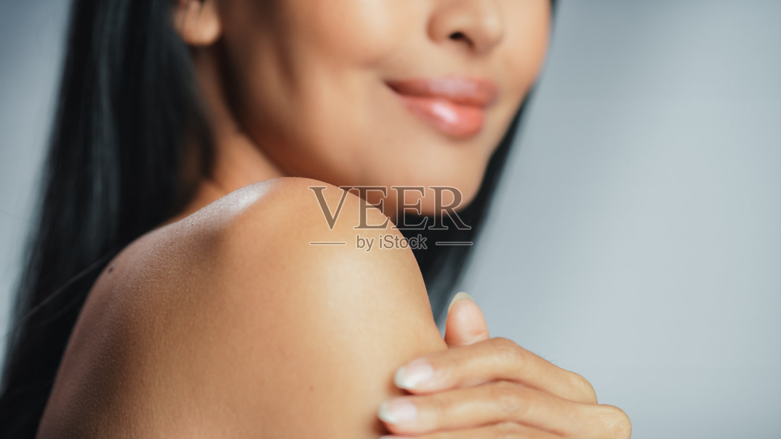 美丽的亚洲女人触摸她完美的柔软的肩膀，脖子，感性的微笑。女性欣赏自己的美丽。天然美容护肤产品。特写肖像与孤立的背景照片摄影图片