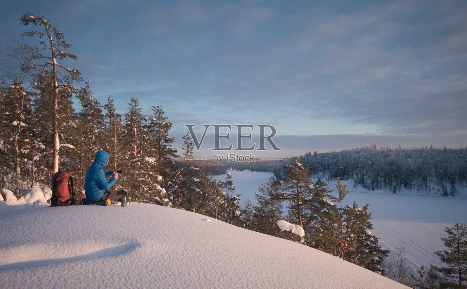 徒步旅行者正在风景如画的白雪覆盖的地区休息。这个男人正在用手机。照片摄影图片