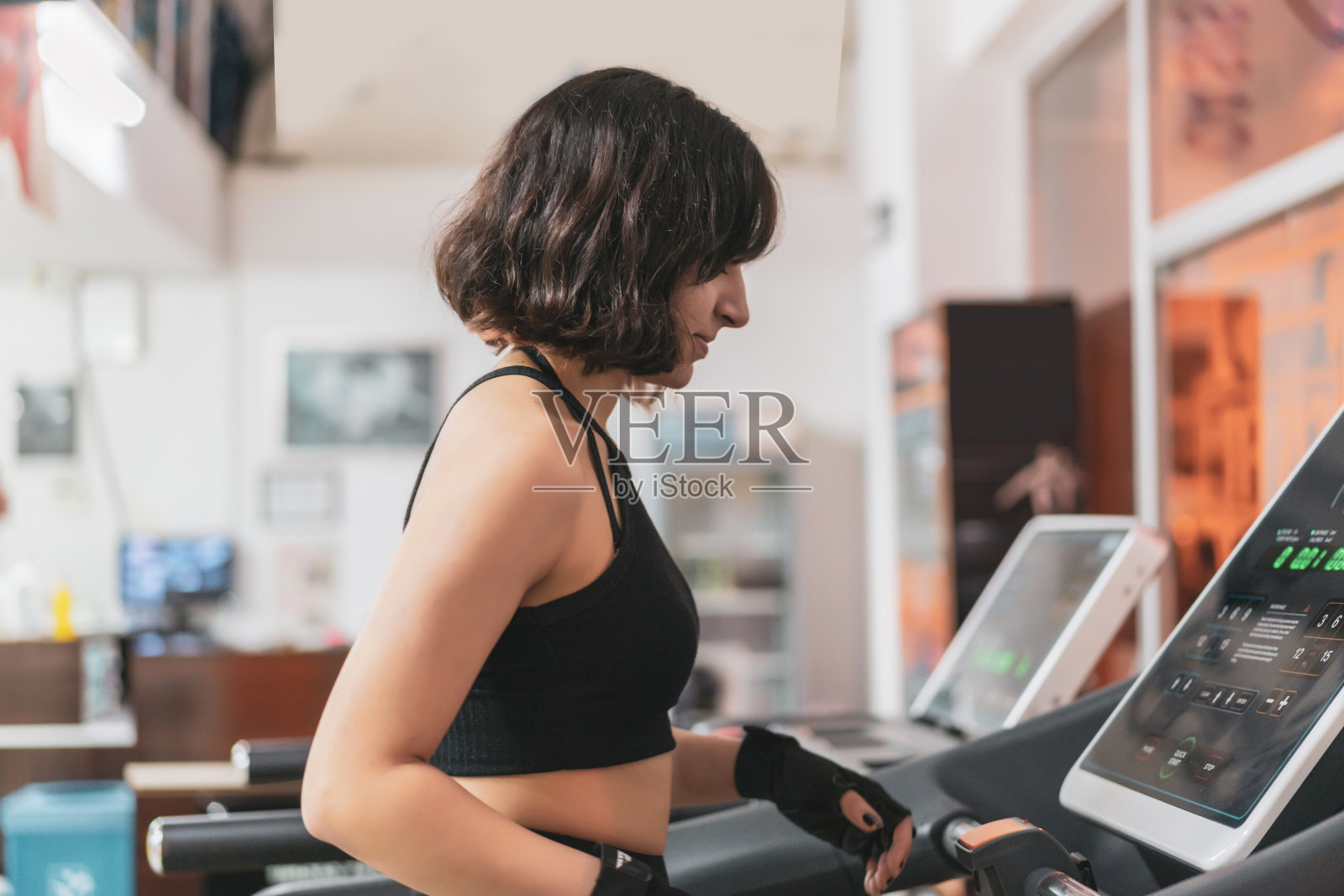 美丽肌肉发达的女人在跑步机上跑步的侧面视图。照片摄影图片