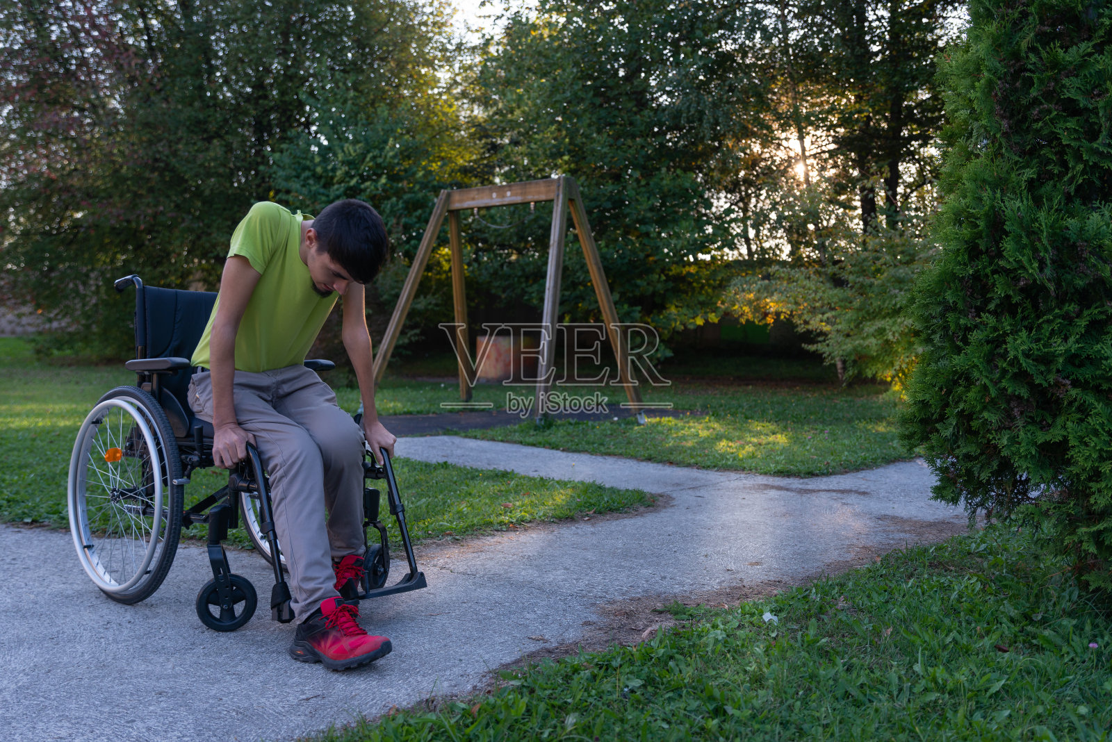 一个真正的残疾人坐在轮椅上，通过电子设备，电脑，电话与世界交流。照片摄影图片