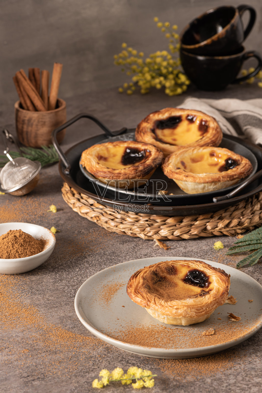 传统的葡萄牙糕点Pastel de Nata或Pastel de Belém与肉桂粉在一个传统的托盘上质朴的板。蛋挞照片摄影图片