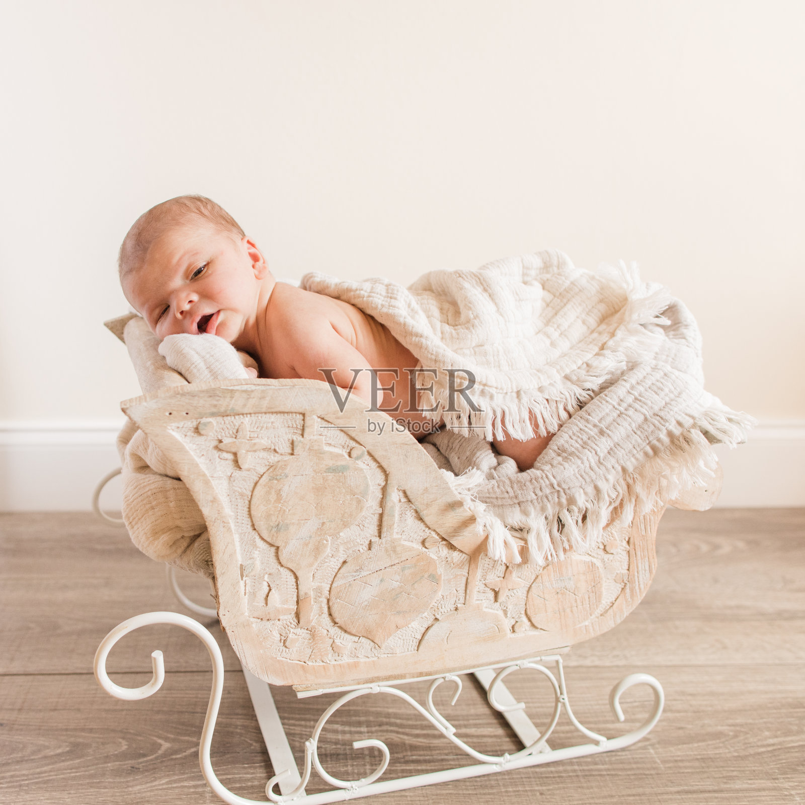 新生的婴儿男孩依偎在一个木制的雪橇与中性的毯子，场景和背景照片摄影图片