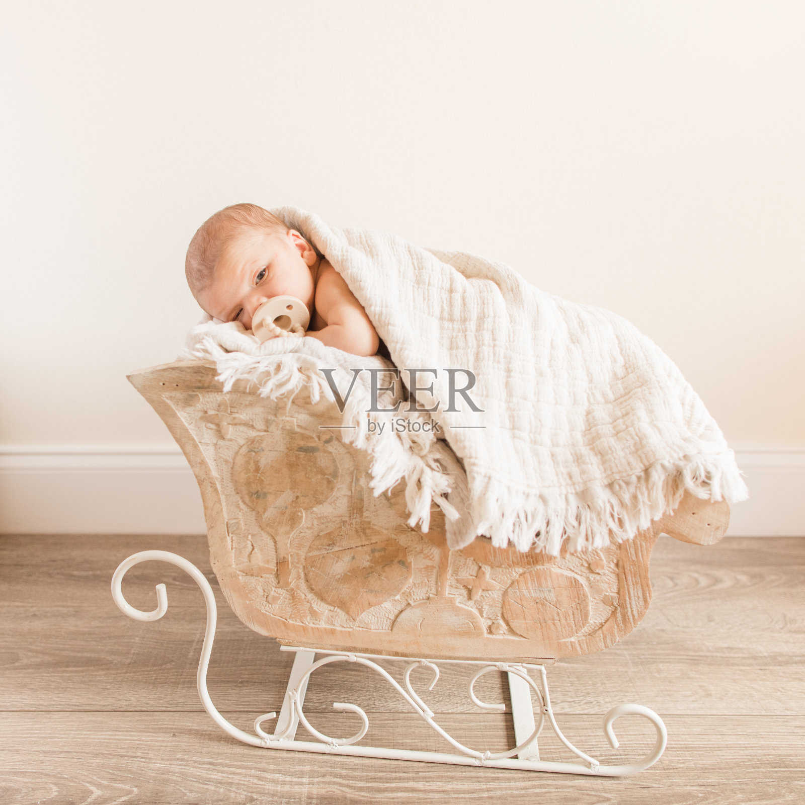 新生的婴儿男孩依偎在一个木制的雪橇与中性的毯子，场景和背景照片摄影图片