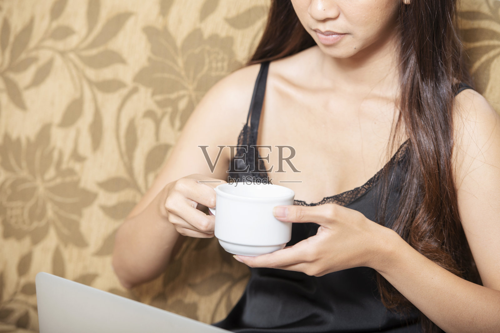 亚洲妇女坐着使用笔记本电脑和一杯咖啡照片摄影图片