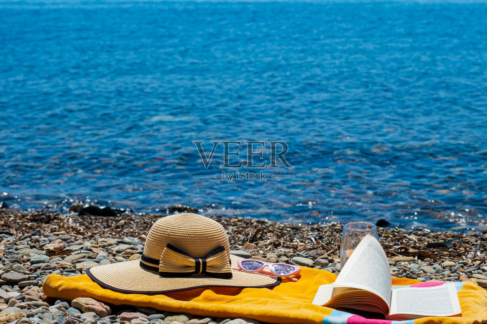 暑假带着毛巾，帽子和一本书，在海滩上照片摄影图片