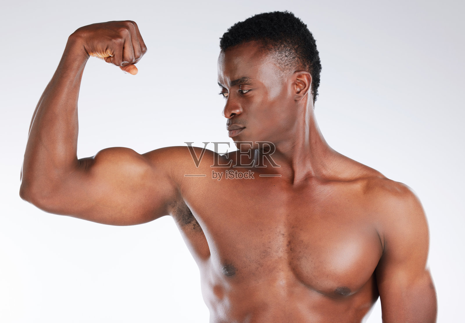 一个英俊的年轻男子在工作室摆姿势时弯曲他的二头肌的照片照片摄影图片