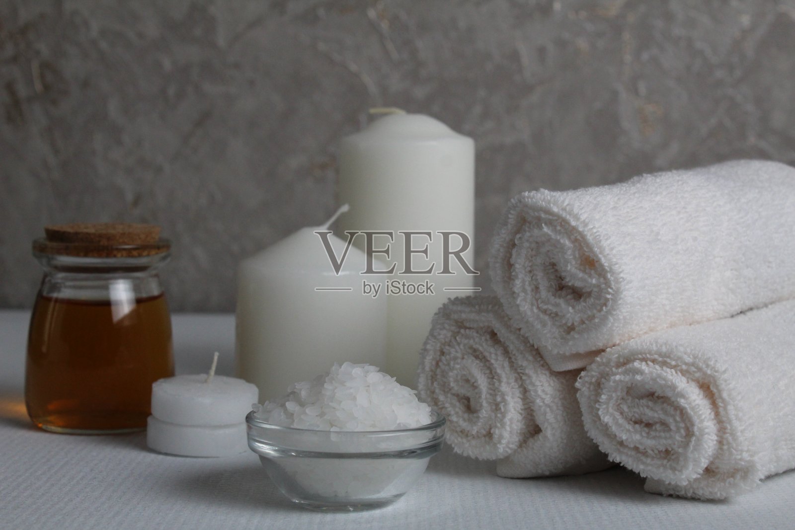 水疗放松按摩居家大豆身体护理。白色的蜡烛毛巾油在一个罐子瓶子擦洗白灰色的背景与文字的空间。美容院照片摄影图片