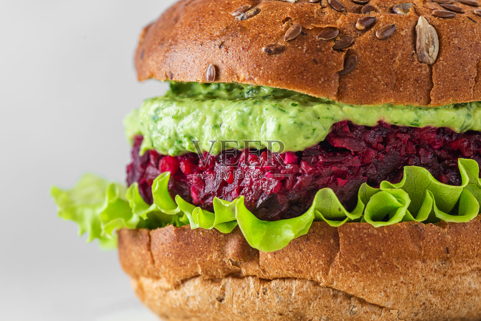 近距离素食汉堡与甜菜，鳄梨酱和生菜沙拉的白色背景。健康的素食照片摄影图片