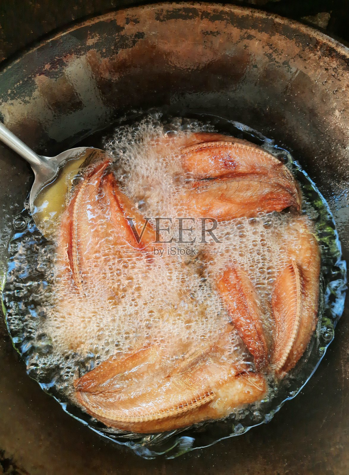 在锅中煎炸黑鱼干-食物的准备。照片摄影图片