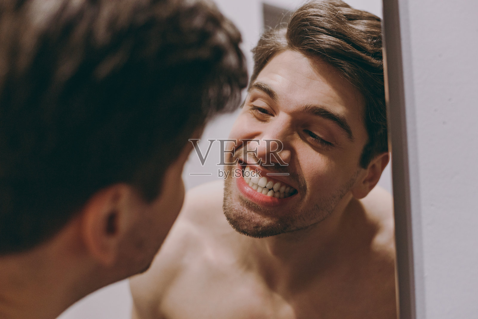 年轻的乐趣满足白种人半裸上身褐发男子20岁映在镜子里看着他白色的牙齿在室内浴室在家里人们保健每天早上例行的生活方式的概念照片摄影图片