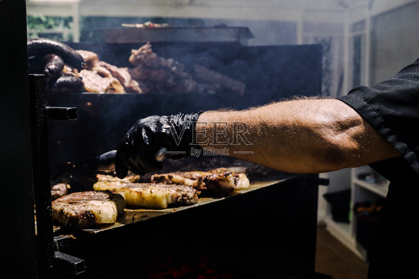 厨师在后院烧烤派对上做烤牛肉——专注于男人的手臂照片摄影图片